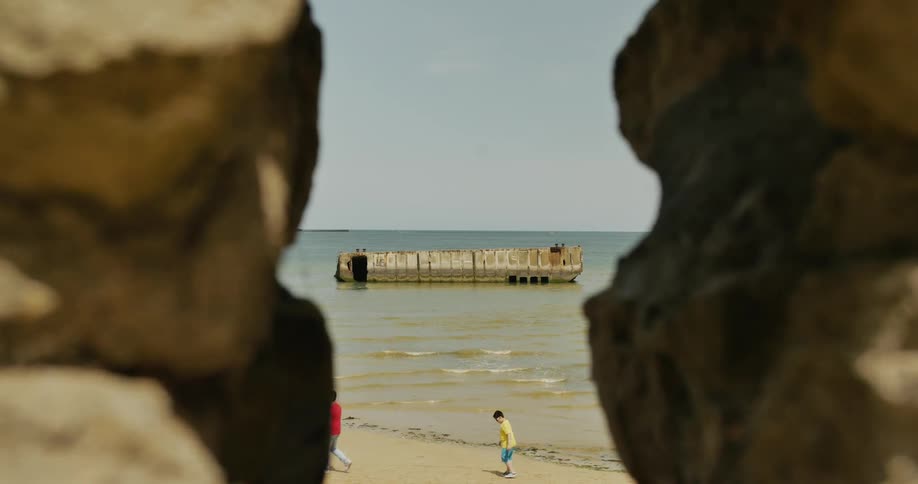 A view through rocks of people walking along a beach