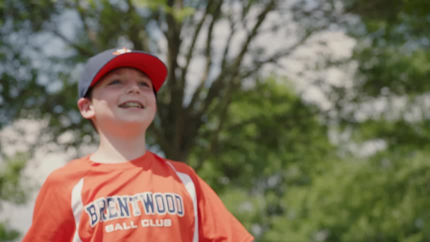 Boy smiles while throwing a baseball