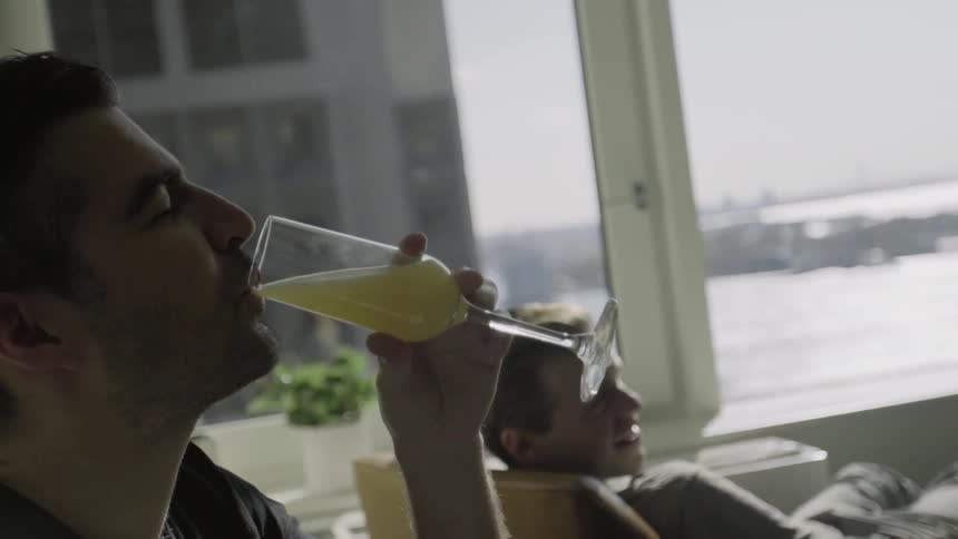 Men sitting in a lounge, while one sips a cocktail