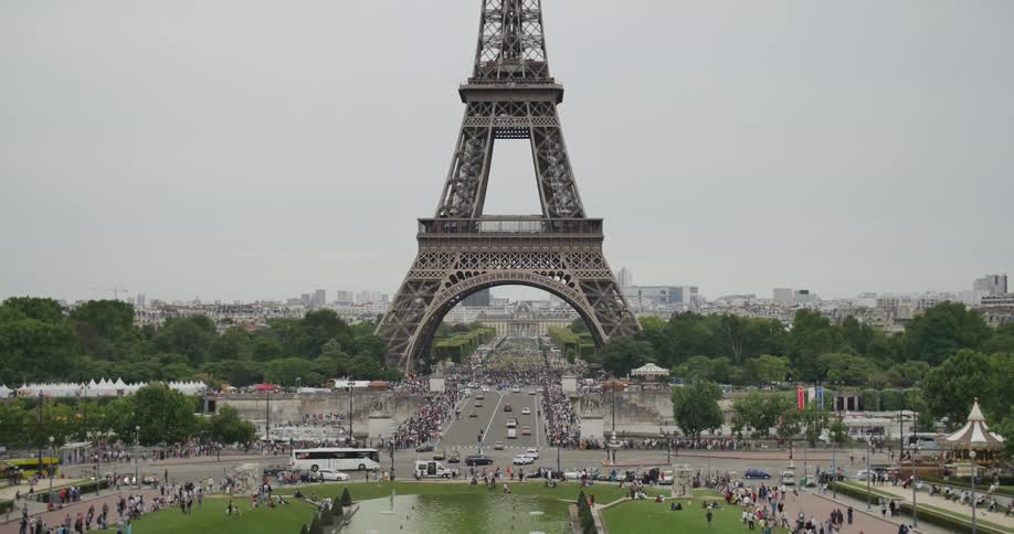Traffic driving by, and people walking around, the eiffel tower
