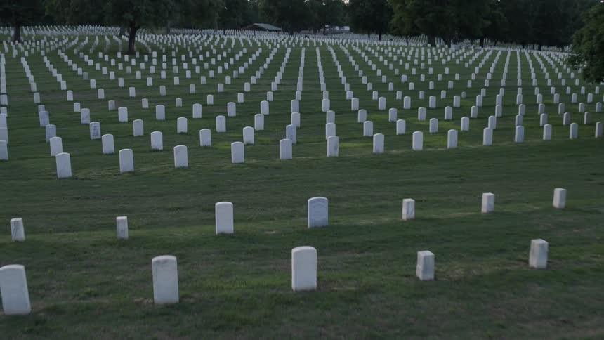 Identical headstones stand in rows in a cemetery