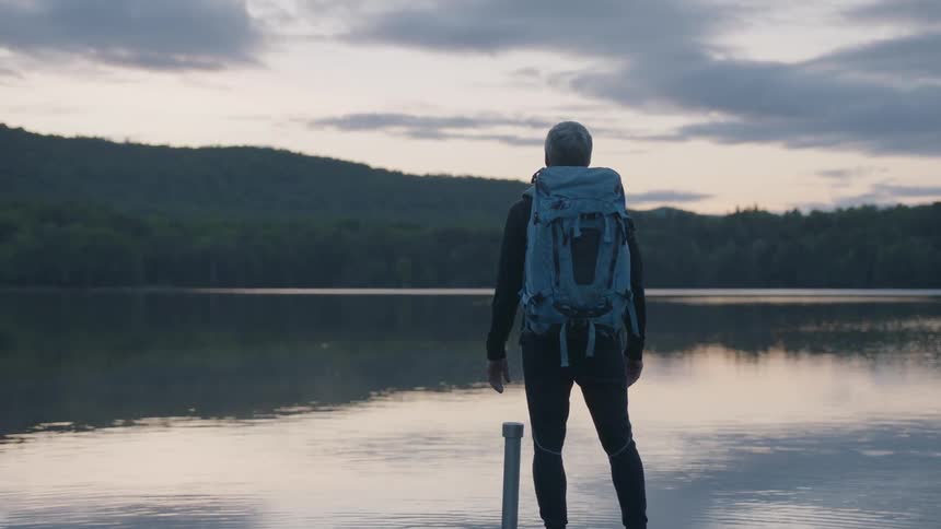 A man is standing by the lake taking in the view
