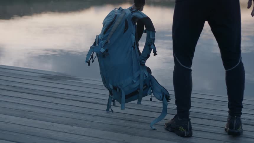 Hiker stands next to a mountain lake at sunset