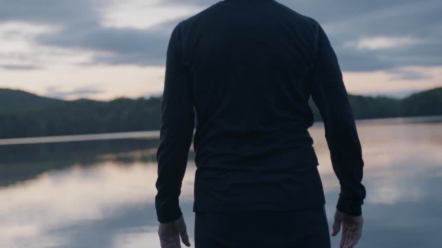 Man stands on a lake dock at sunset
