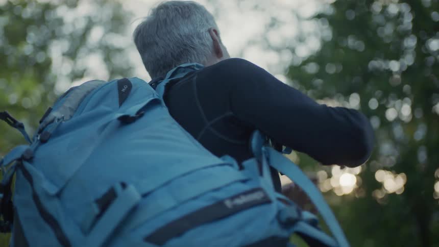 A man picks up a blue backpack