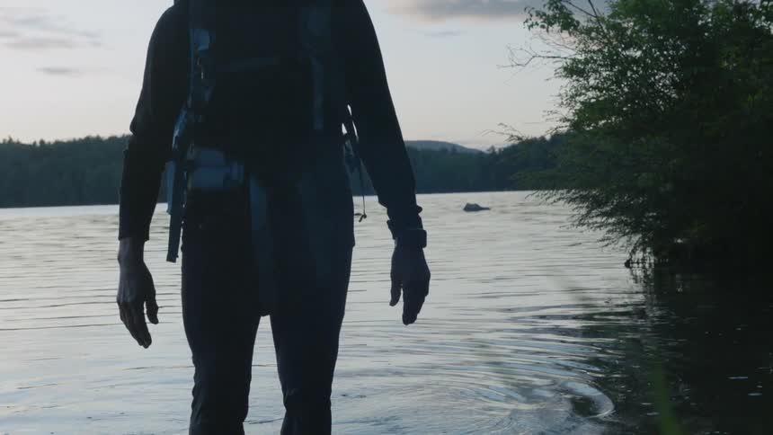 A man wades through ankle deep water in a lake