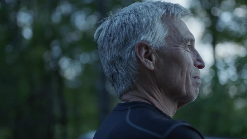 A man smiles while looking towards a forest