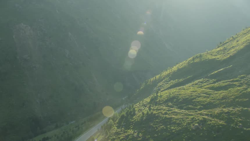 The sun shines down on a mountain road