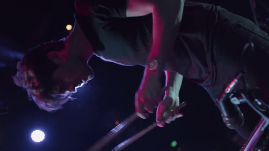 A drummer is playing the drums while standing up