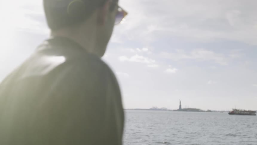 A man watches a boat float on a river