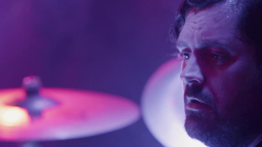 Man nods his head while playing drums