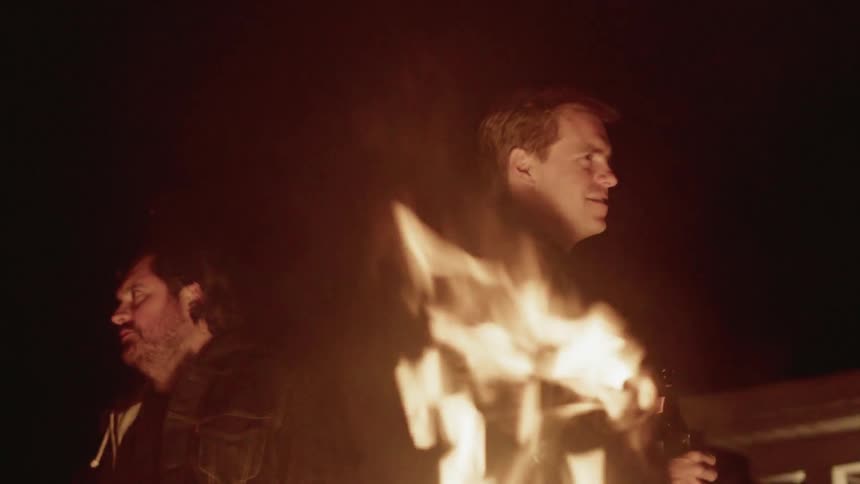 Men stand near a campfire at night
