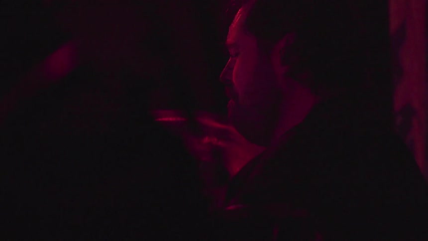 Man playing drums at concert while lights flash over head