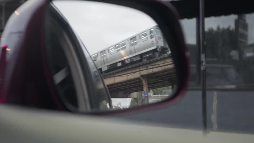 A train is visible in the side view mirror of a car