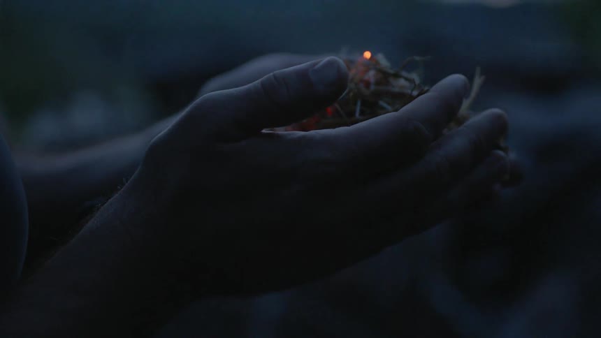 A man holds smoldering debris in his hands