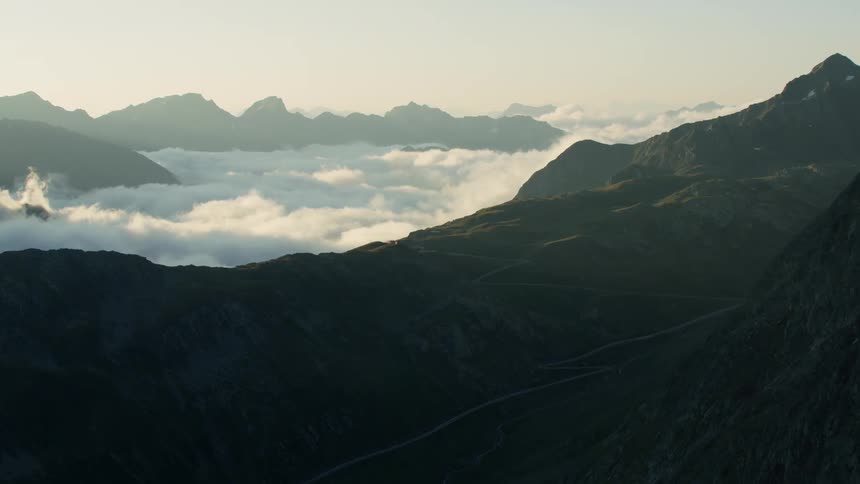 Clouds float in a mountain valley at sunset