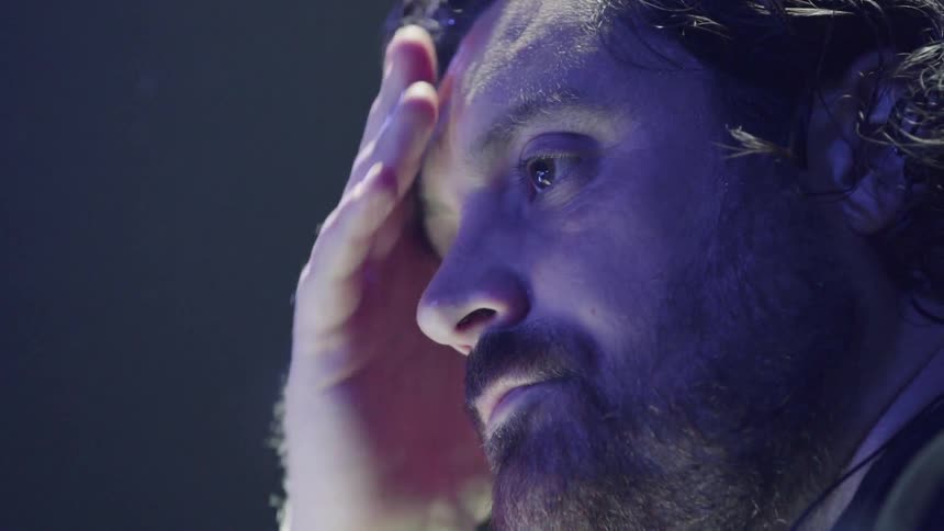 A man talks and wipes his forehead