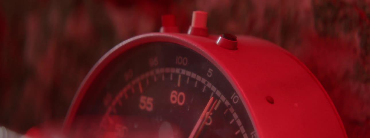 A hand pushes a button on a clock