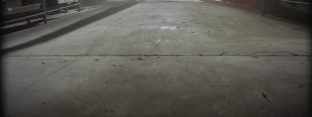 A person walks through a sparse room with concrete floors