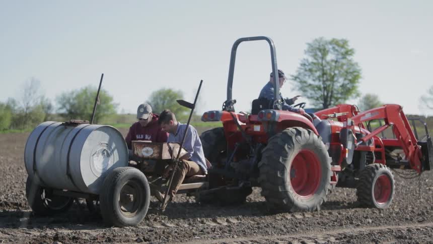 Three men are sitting on a tractor