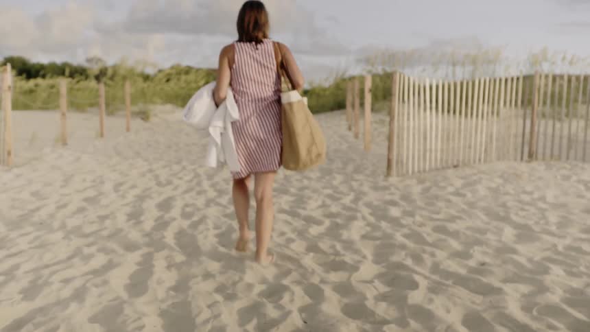 Woman carries a tote bag as she walks on the sand