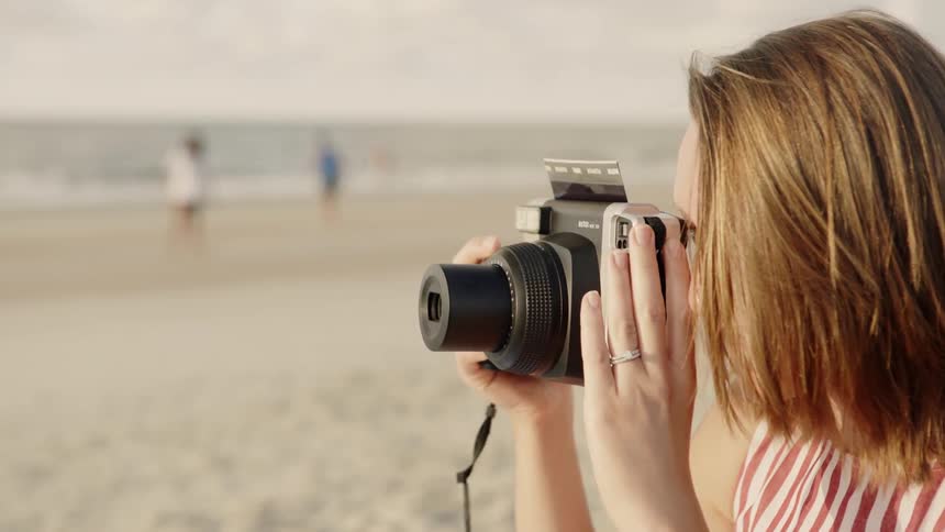Woman takes a photograph on a sandy beach