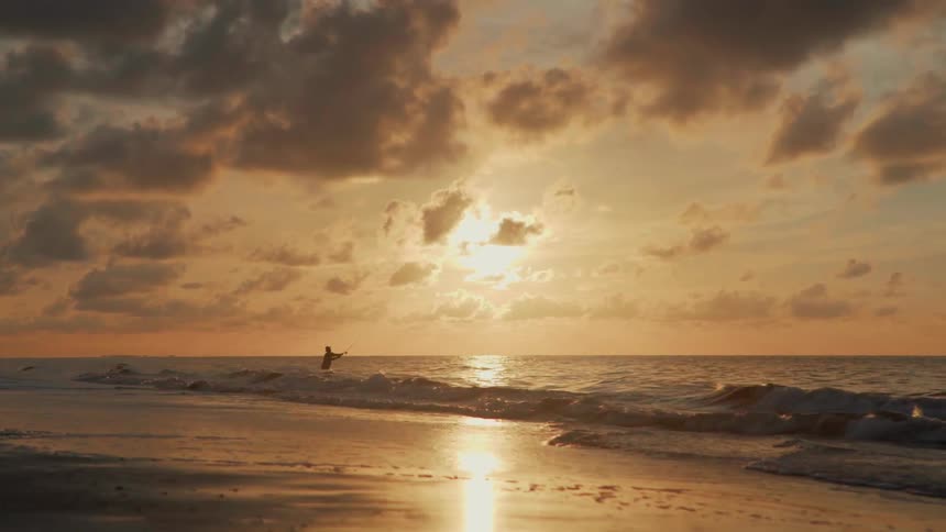 Man stands in the ocean fishing