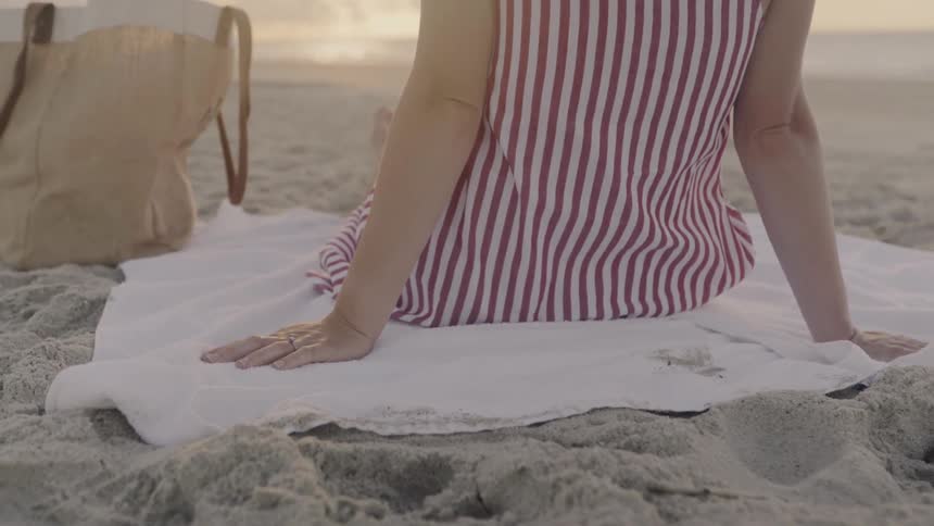 A woman is sitting on a towel on the beach