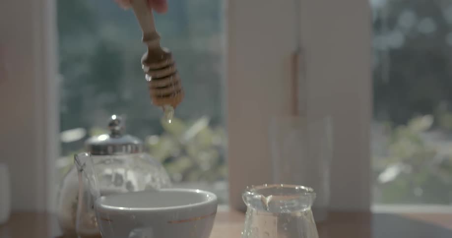A man pours honey into a teacup