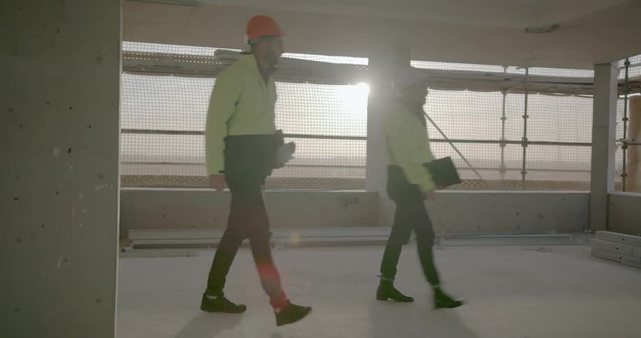Two construction workers walk through a construction site