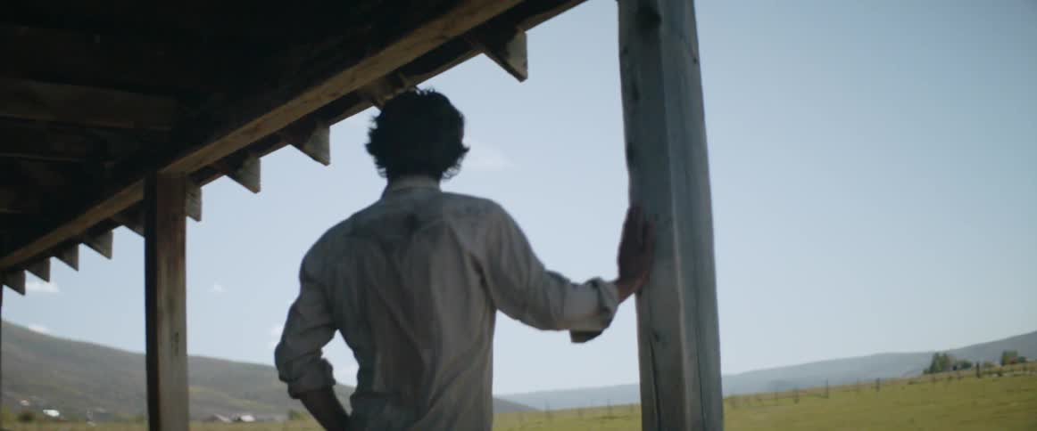 A sweaty man stands under an awning