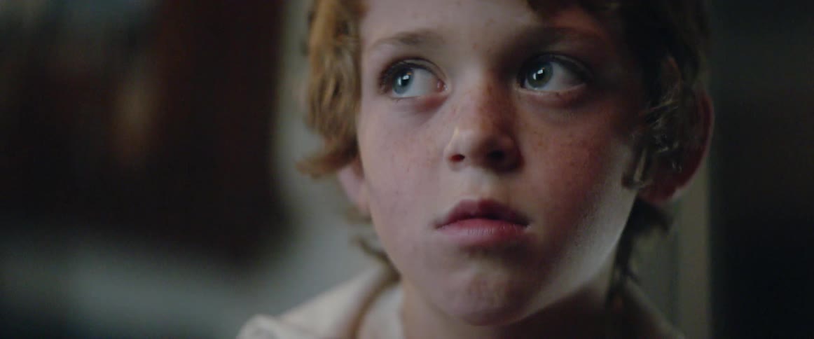 A young boy looks up at the television, then turns away in thought