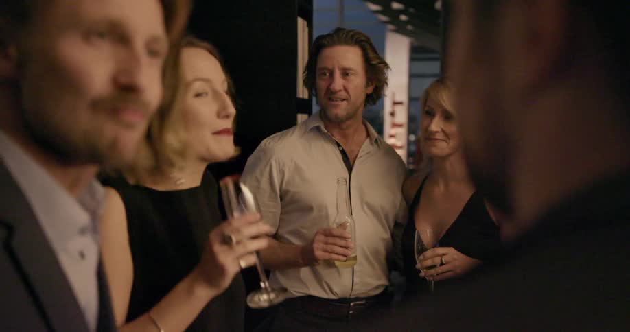 Men and women stand around talking while holding beverage glasses and bottles