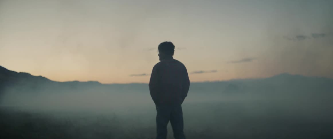 A man stands out in a hazy and dusty field