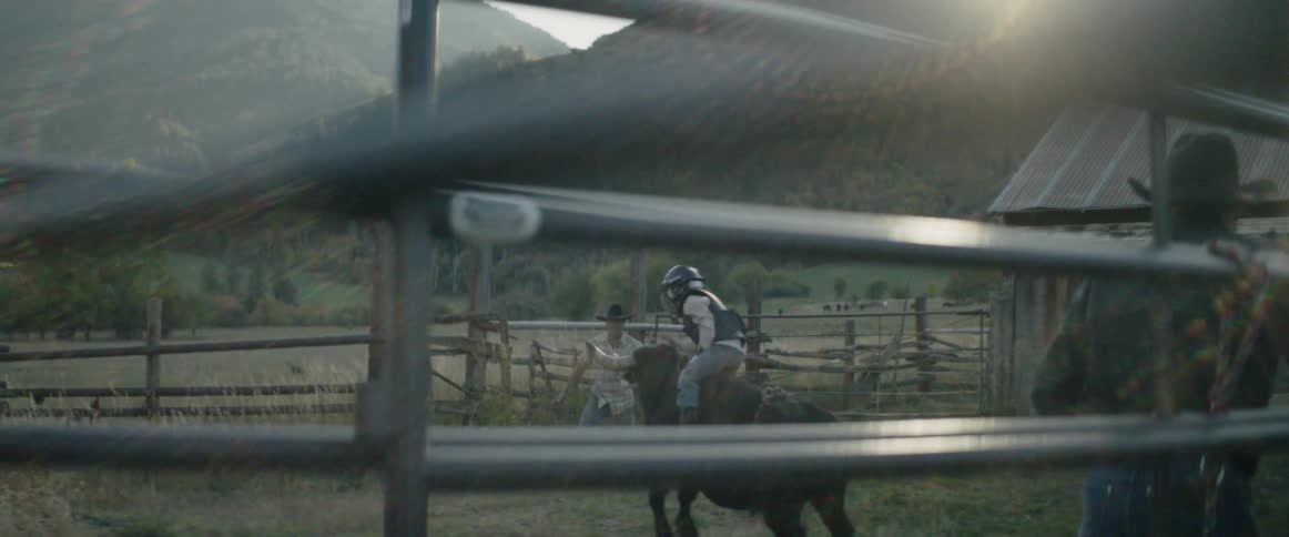 A man is riding a bull while others watch