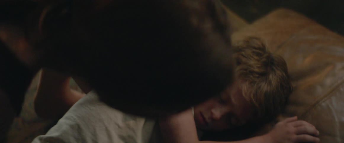 A sleeping boy is gently carried to bed late at night