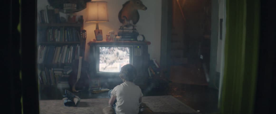 A young boy watching television at night, lost in a quiet moment