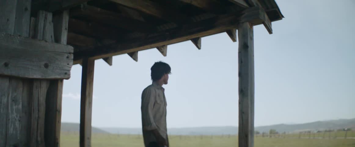 Man stands beneath an awning on a ranch