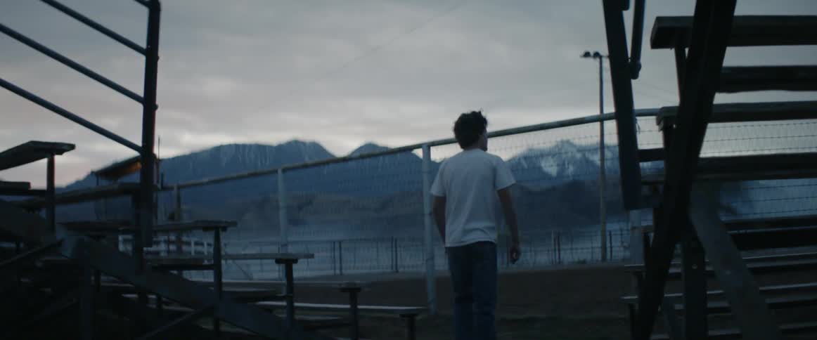 A young man walks towards a fence at a bull riding arena