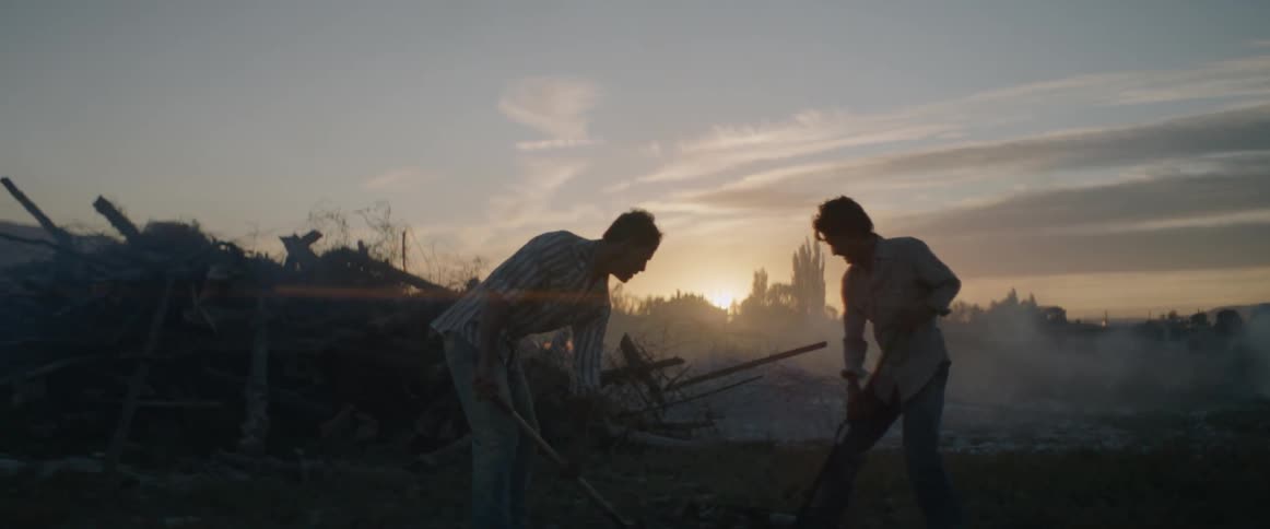 Two men digging near a smoking pile of debris