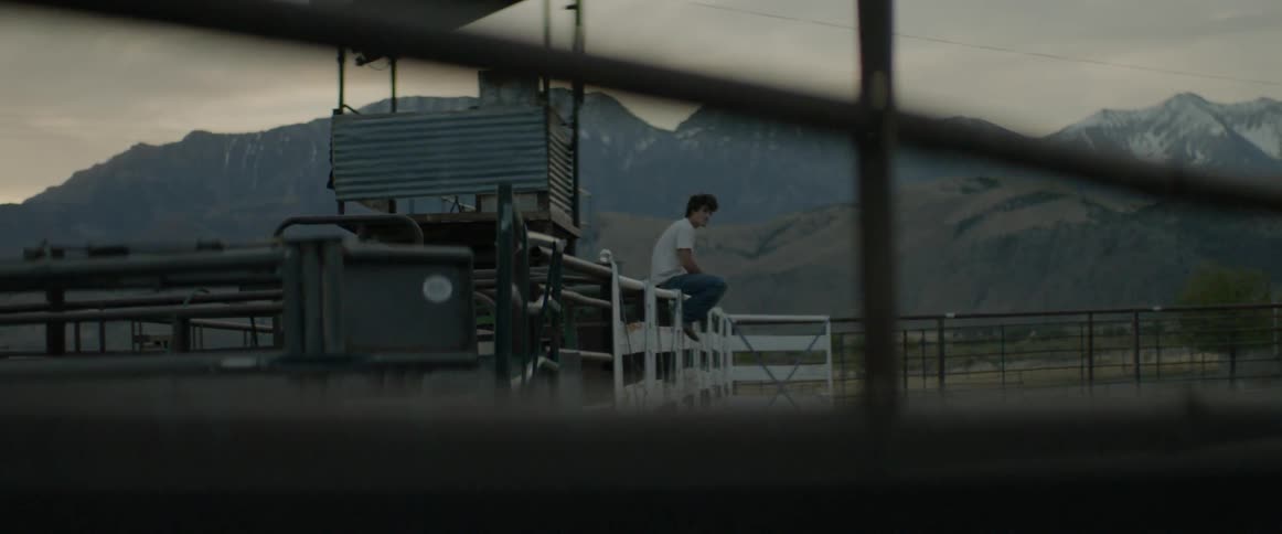 A man is sitting on the edge of a wooden fence