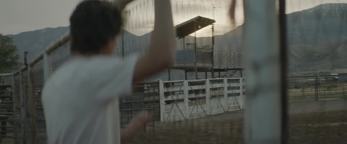 Man stands looks at an empty rodeo arena at sunset