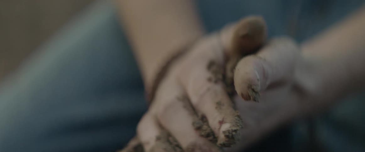 Person picking up and rubbing dirt in their hands