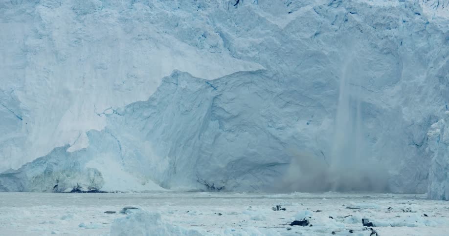 The large wall of ice begins to melt into the water
