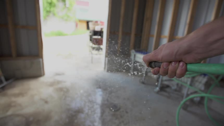 Person spraying water on the ground from a hose