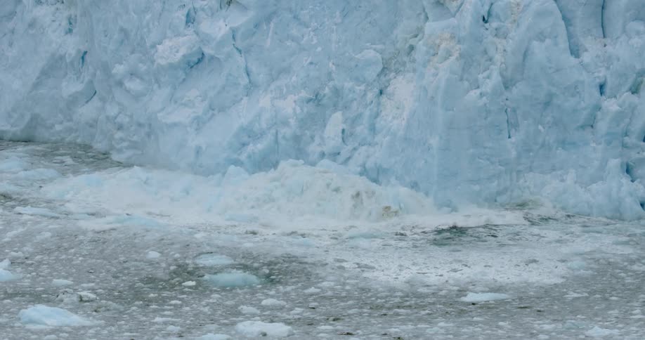 Snow collapses from the side of a glacier