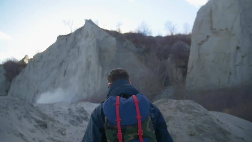 Man climbs a rocky mountain on a cloudy day
