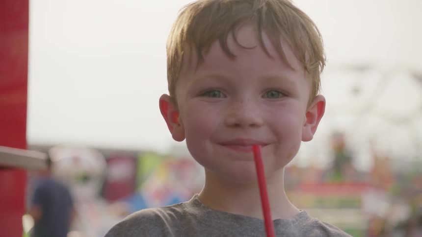 A boy holds an icee drink at a carnival