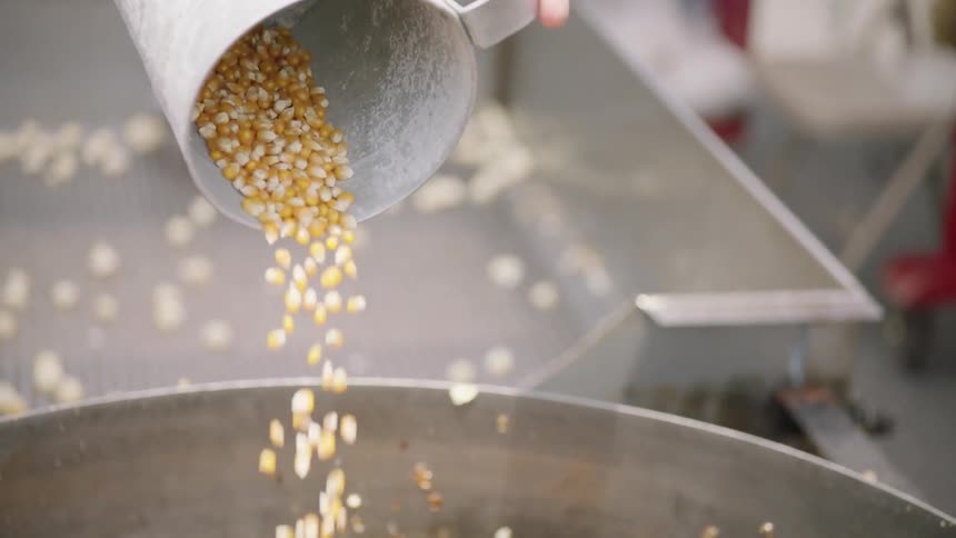 Corn kernels are poured into a large kettle