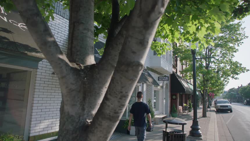 A young man walks down a city sidewalk